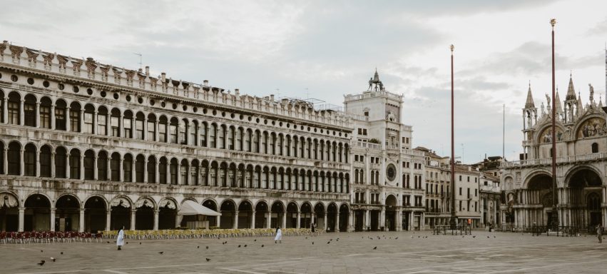 Piazza San Marco in Venedig, umgeben von historischen Gebäuden und Säulen.